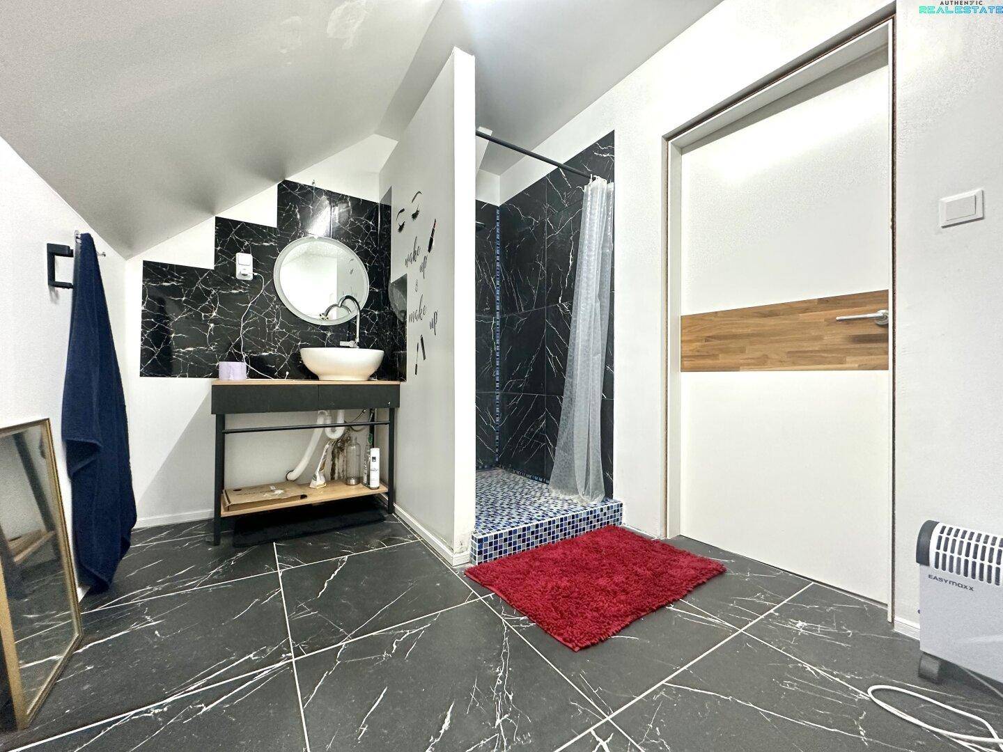 Modernes Badezimmer im Dachgeschoss mit schwarzem Fliesenboden und offener Dusche.