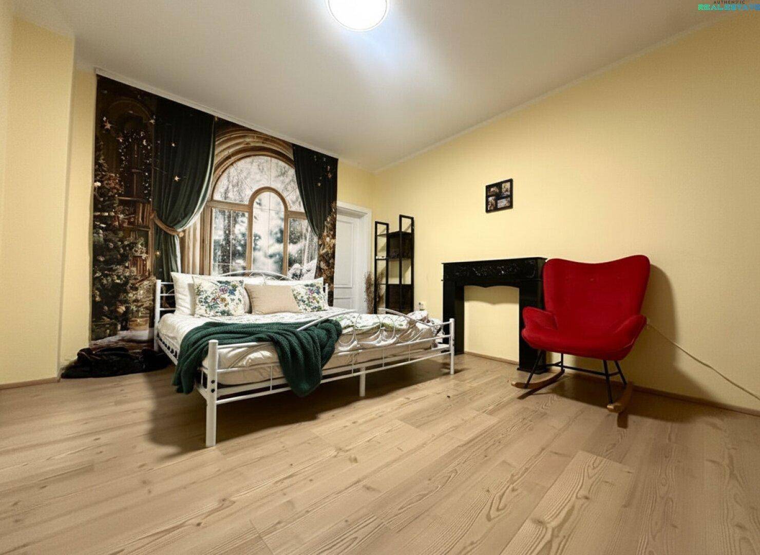 Schlafzimmer mit gelben Wänden, Holzboden und dekorativem Wandbild.