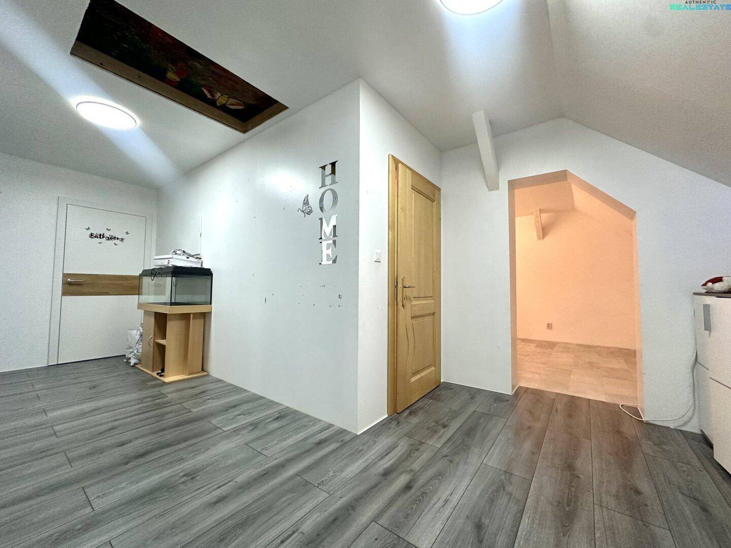 Heller Flur im Dachgeschoss mit Holztür und modernem Laminatboden.