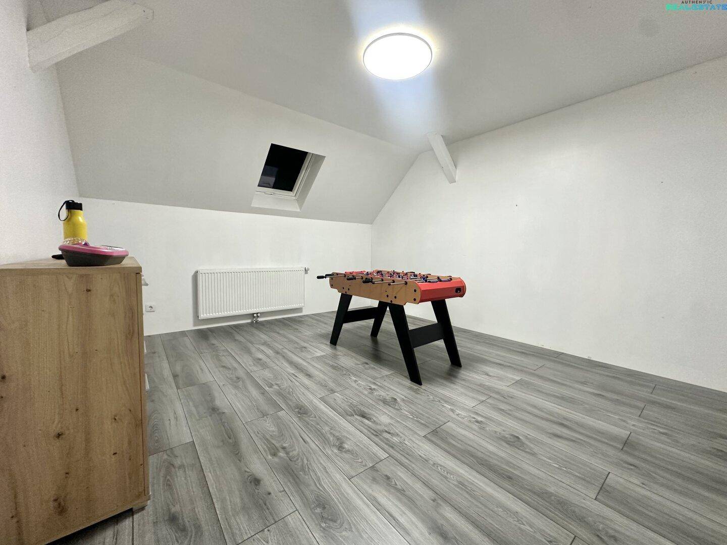 Dachzimmer mit Laminatboden, Heizkörper und Dachfenster, ideal als Kinderzimmer.