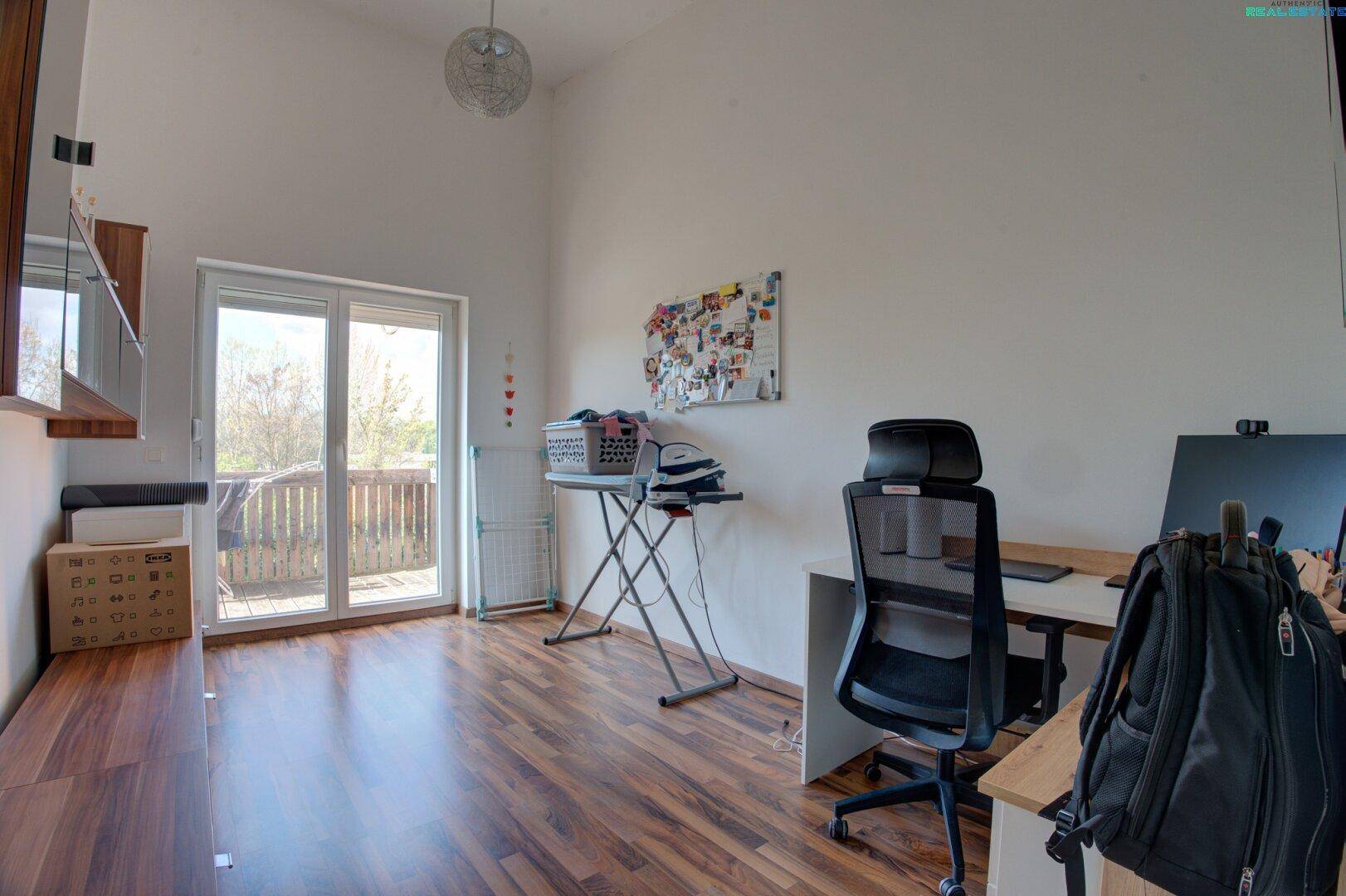 Helles Zimmer mit Holzboden, Schreibtisch und direktem Zugang zu einem Balkon.