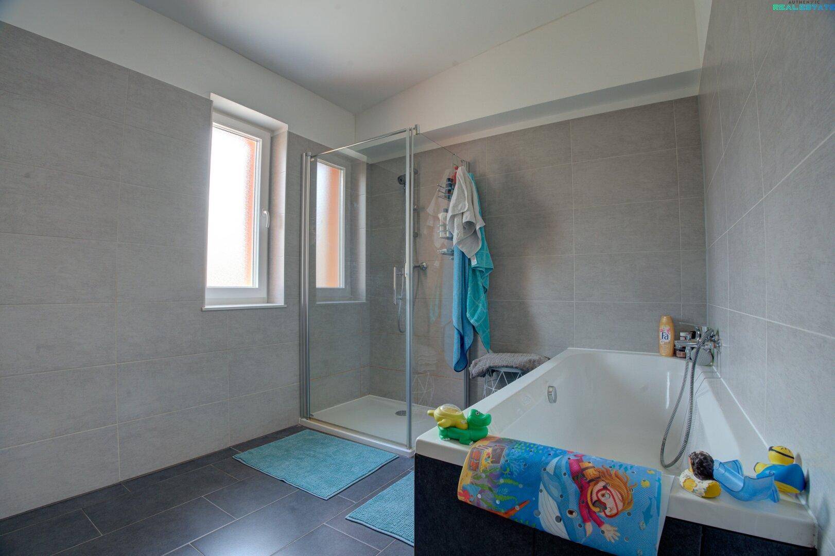 Modernes Badezimmer mit Badewanne, Duschkabine und einem Fenster für Tageslicht.