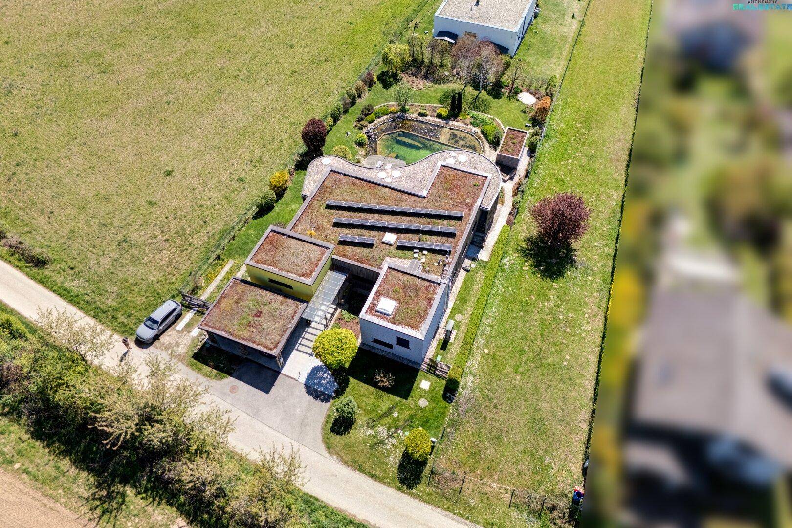 Vogelperspektive des modernen Wohnhauses mit Gründächern, Solaranlage und gepflegtem Gartenbereich.