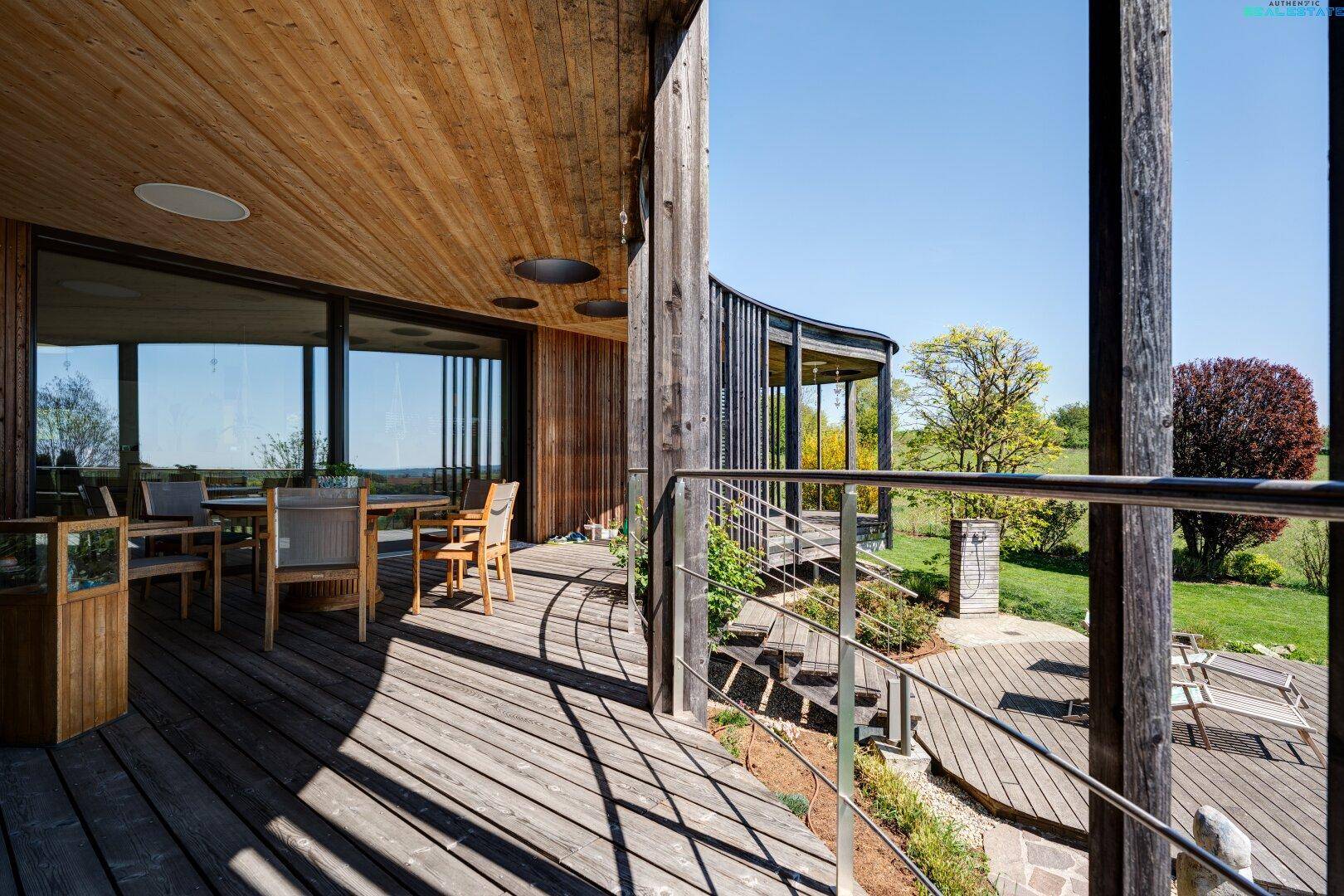 Gemütlicher Essbereich auf der überdachten Holzterrasse mit Blick ins Grüne.