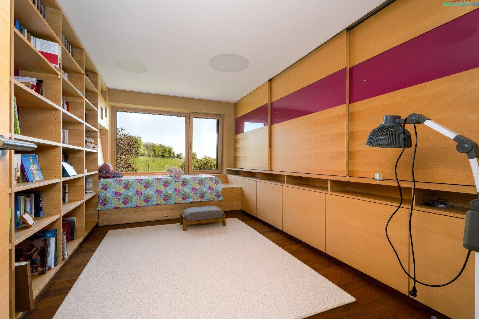 Helles Arbeitszimmer mit eingebauten Bücherregalen, Fensterbank als Sitzgelegenheit und Blick ins Grüne.