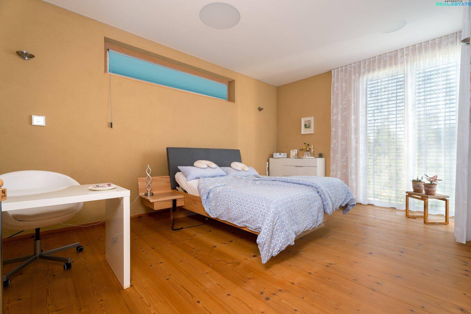 Gemütliches Schlafzimmer mit Holzboden, großem Fenster und Zugang zur Terrasse.
