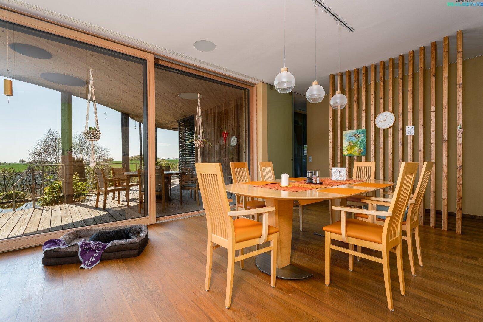 Heller Essbereich mit Holztisch, Stühlen und großen Schiebetüren zur Terrasse.