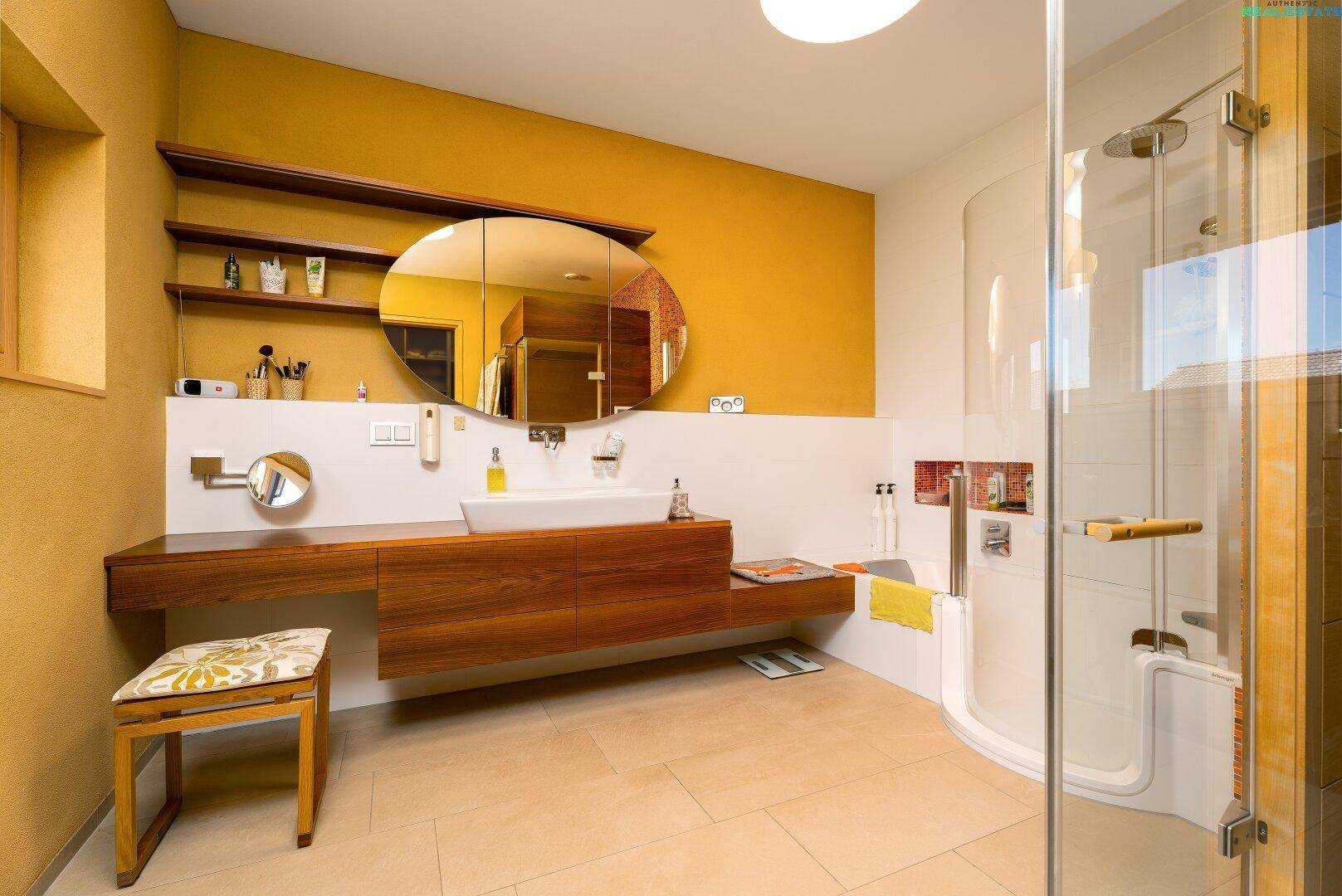 Modernes Badezimmer mit Einzelwaschbecken, großer Dusche und warmen Farbtönen.