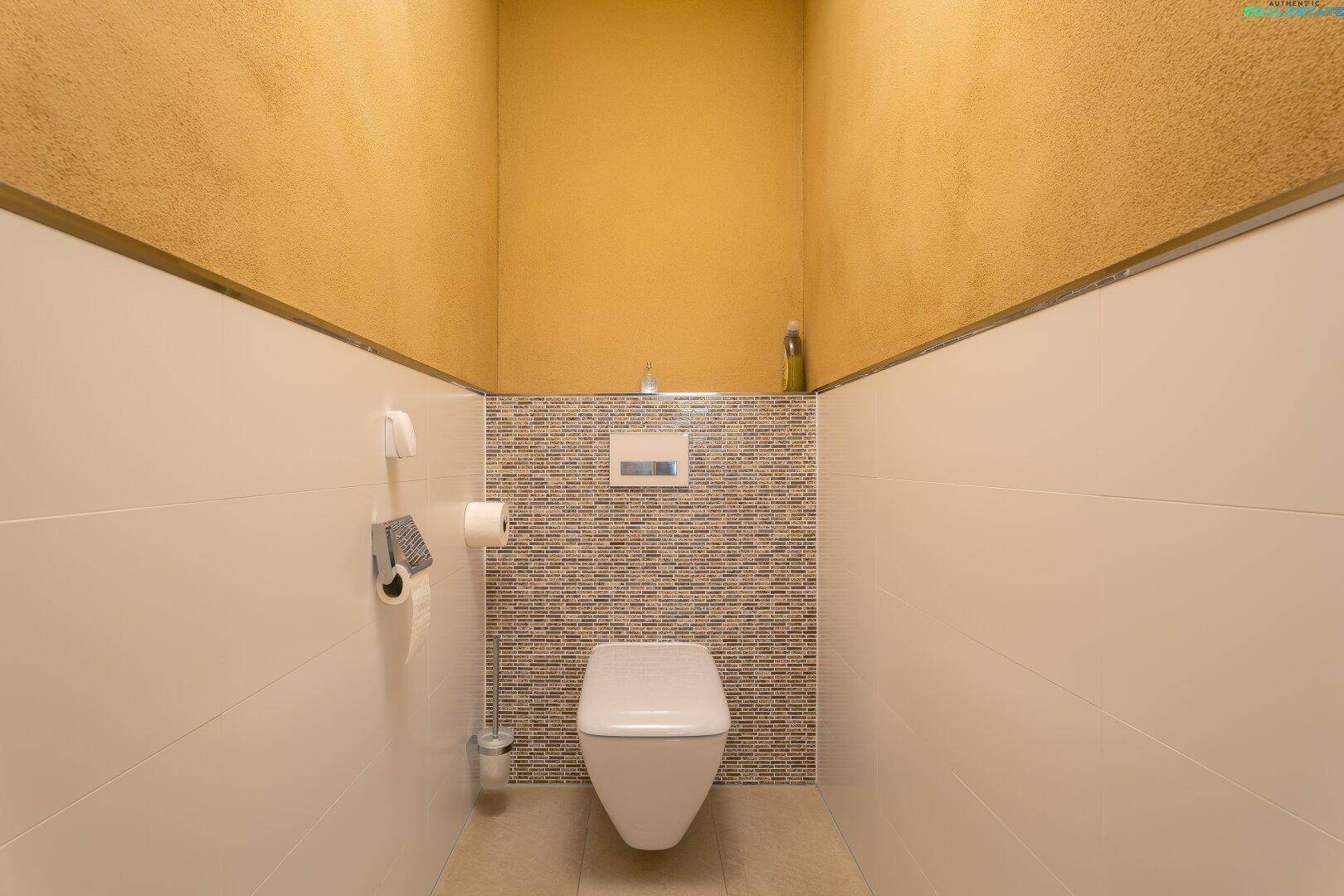 Separates WC mit Wand-WC und modernen Fliesen an der Wand.