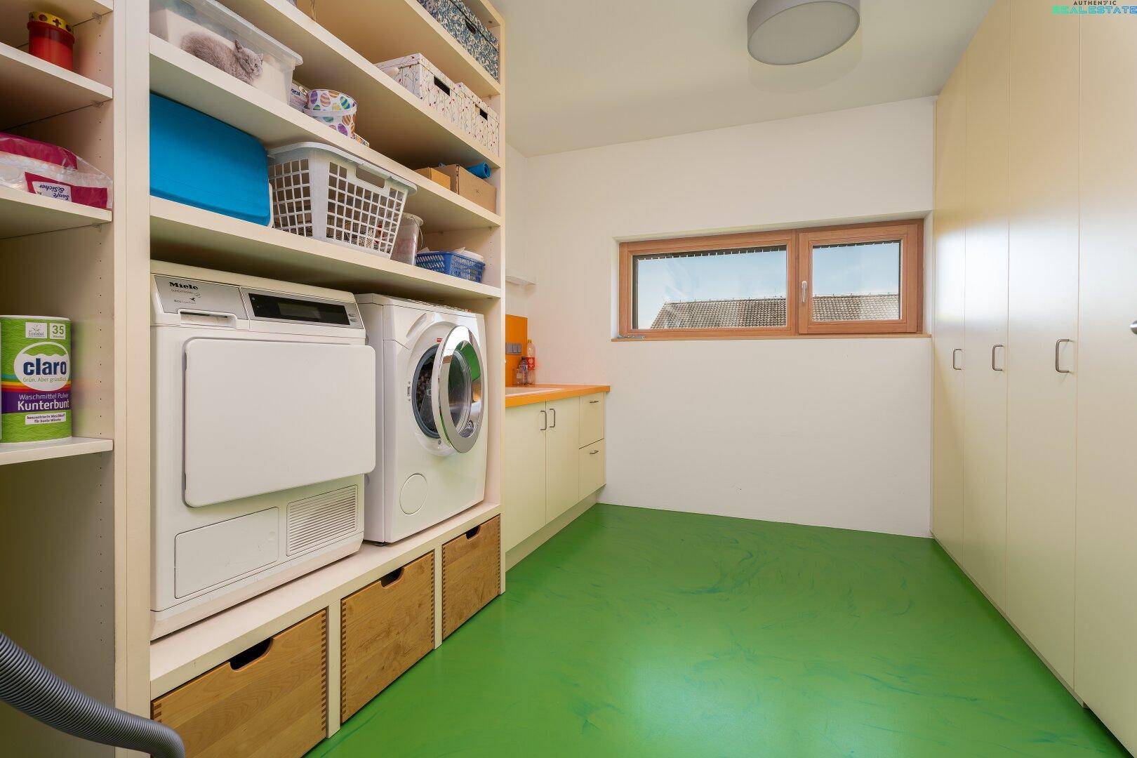 Praktischer Hauswirtschaftsraum mit Waschmaschine, Trockner und viel Stauraum.