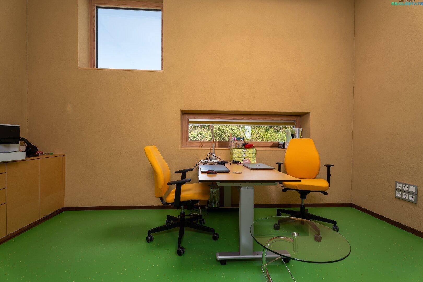 Modernes Büro mit Schreibtisch, ergonomischen Stühlen und Blick auf die Natur.
