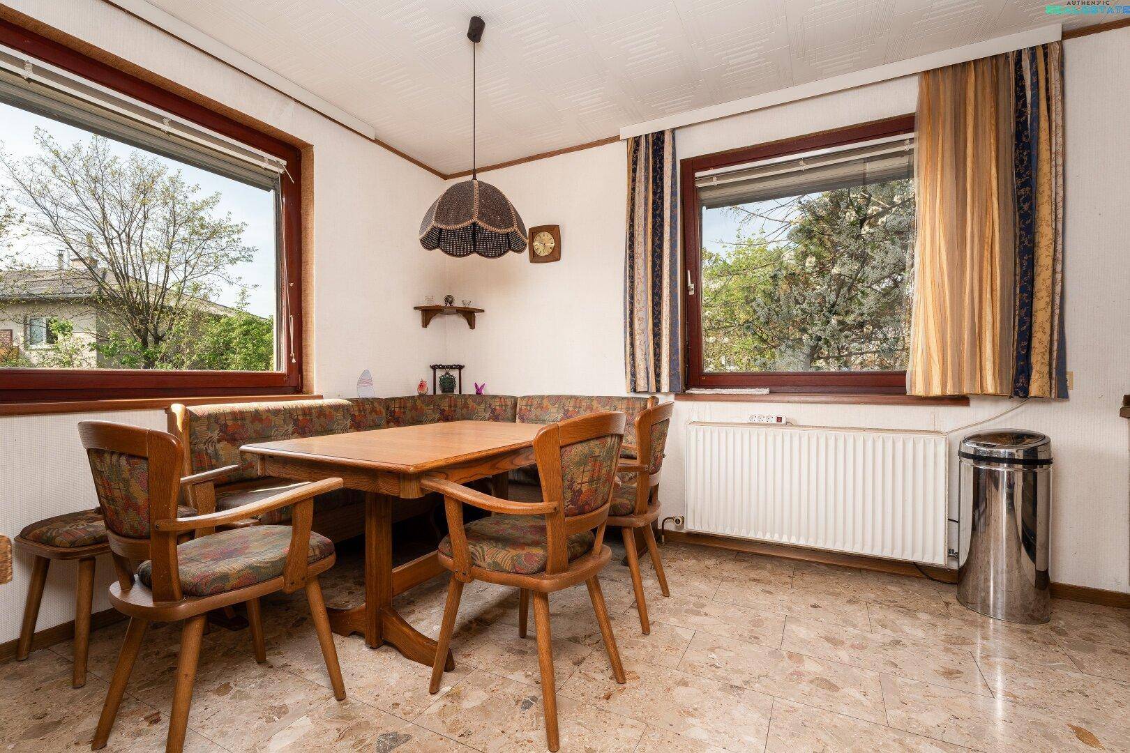 Gemütlicher Essbereich mit Eckbank und Holztisch, umgeben von großen Fenstern.