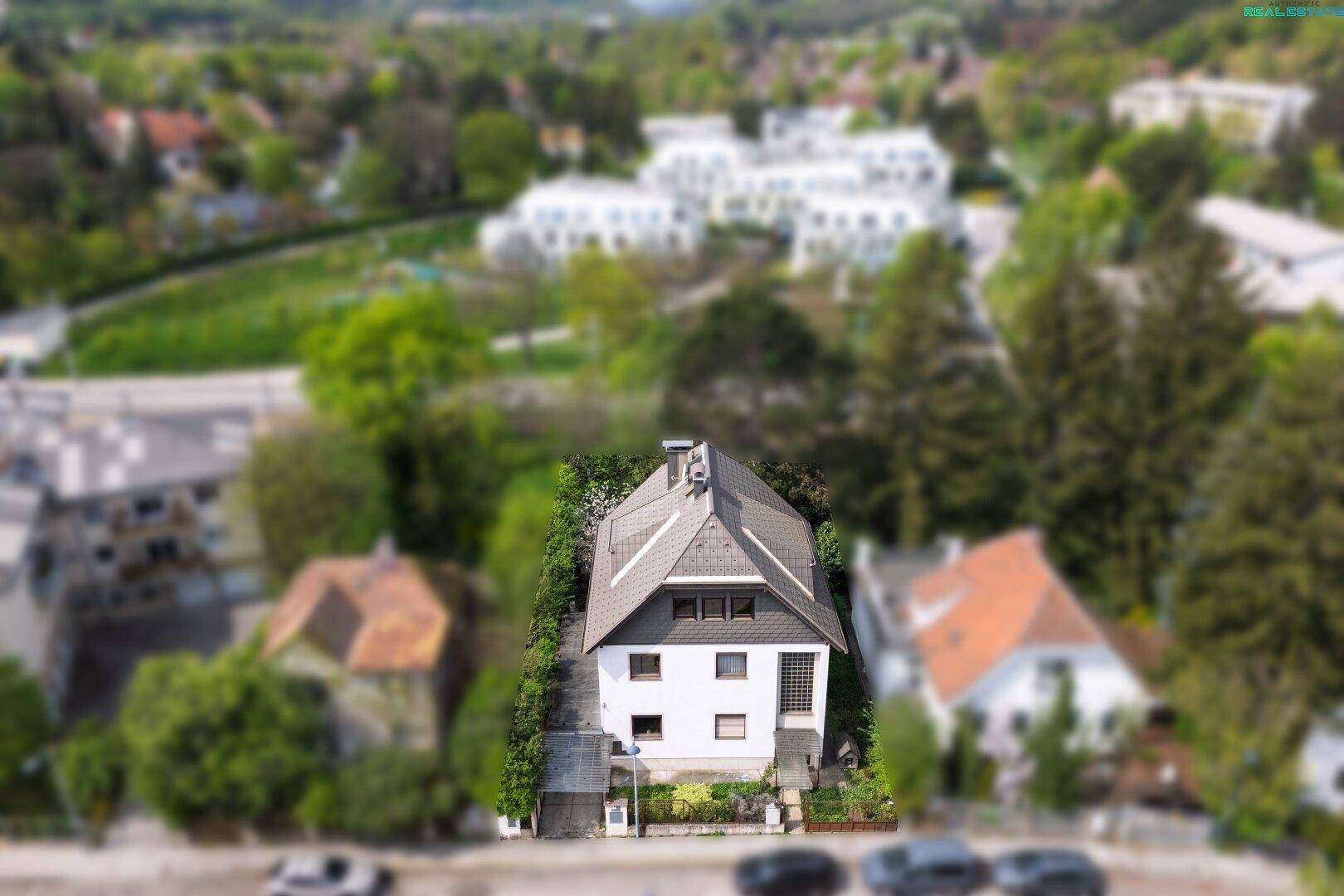 Drohnenaufnahme eines freistehenden Hauses mit gepflegtem Garten und umliegenden Bäumen.