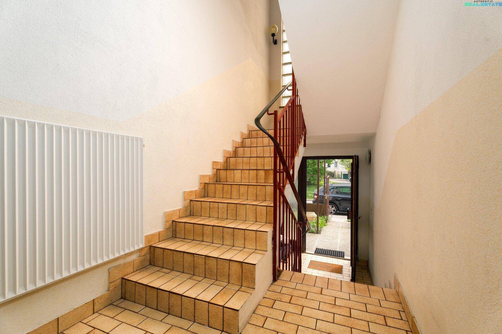 Eingangsbereich mit gefliestem Boden und einer Treppe, die in die oberen Stockwerke führt.