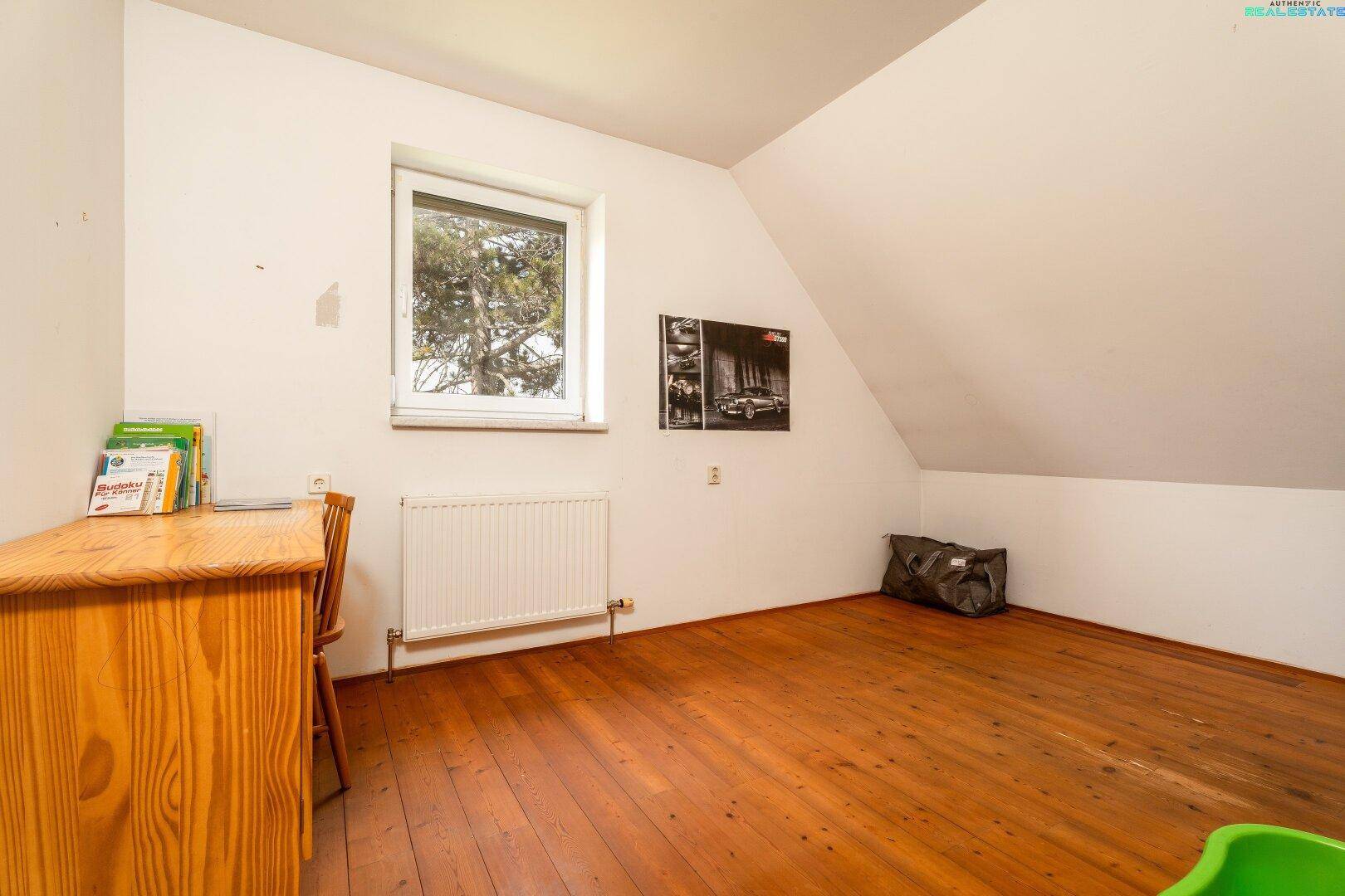 Helles Zimmer im Dachgeschoss mit Holzboden und Schreibtisch, ideal als Kinder- oder Arbeitszimmer.