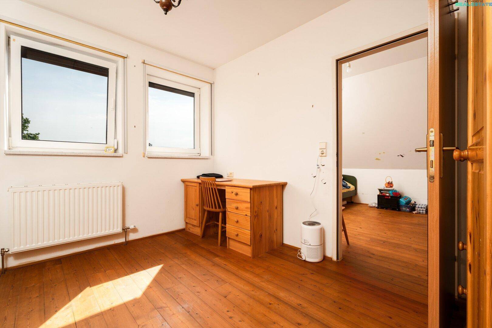 Geräumiges Zimmer im Dachgeschoss mit Holzboden und zwei Fenstern, bietet viel Licht.