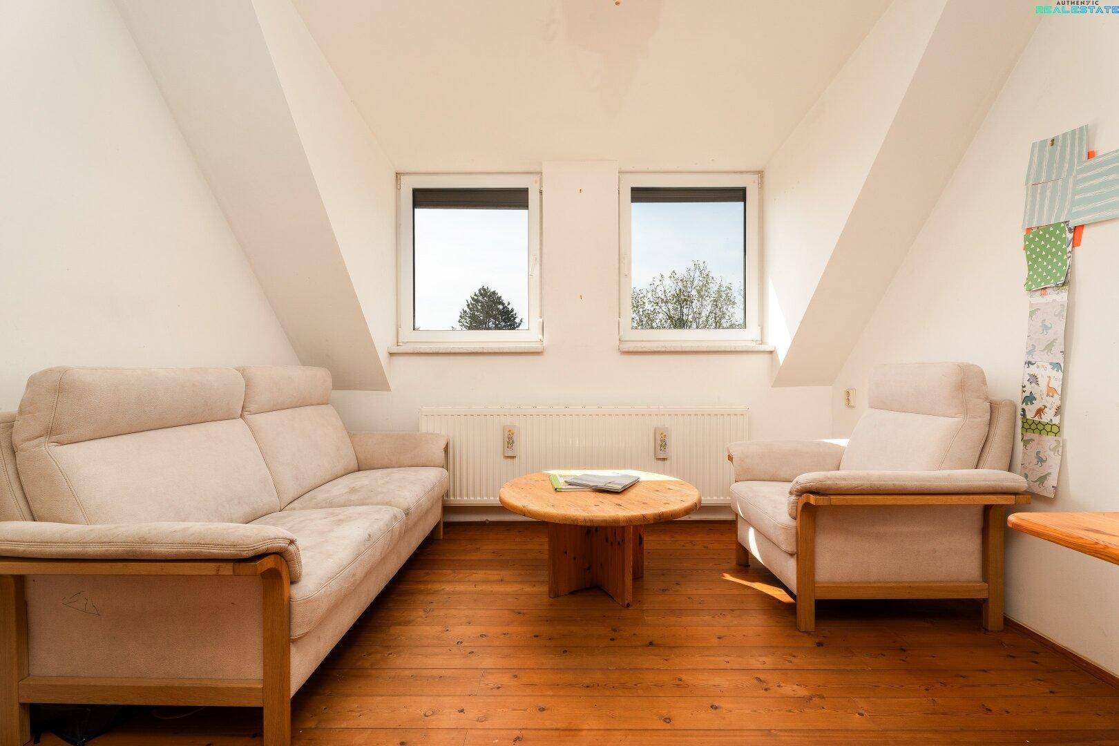 Gemütliches Wohnzimmer im Dachgeschoss mit Holzboden, bequemen Sofas und viel Tageslicht.