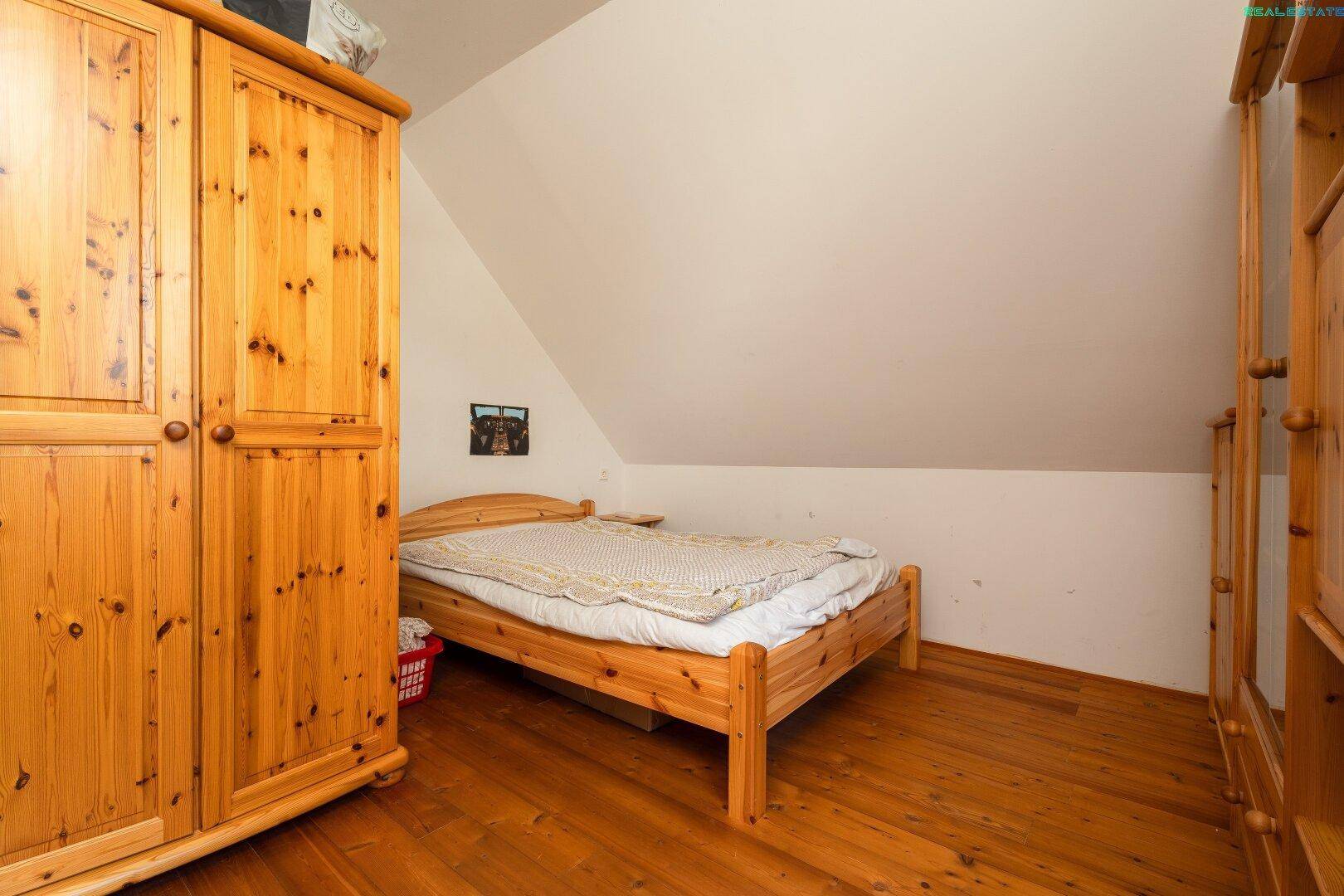 Schlafzimmer im Dachgeschoss mit Holzboden und Holzmöbeln, bietet eine warme Atmosphäre.
