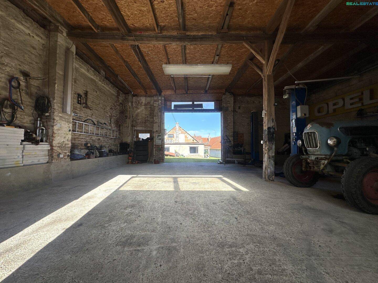 Geräumige Garage oder Werkstatt mit hohen Decken, Betonboden und Blick ins Grüne.