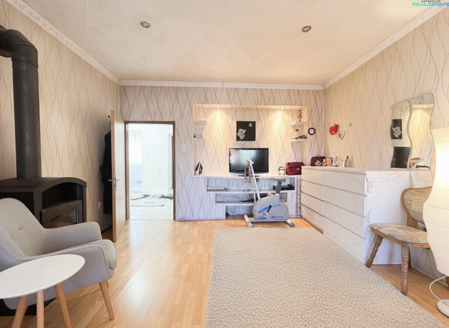 Wohnbereich mit Holzboden, modernem Holzofen und einem Arbeitsplatz.