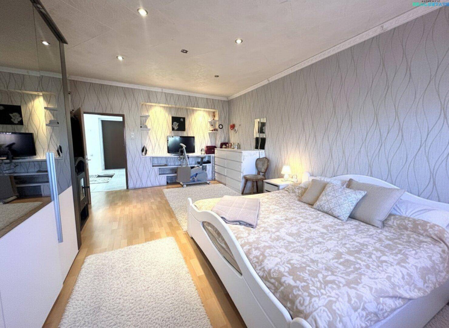 Gemütliches Schlafzimmer mit Holzboden, Schreibtischbereich und dekorativer Tapete.