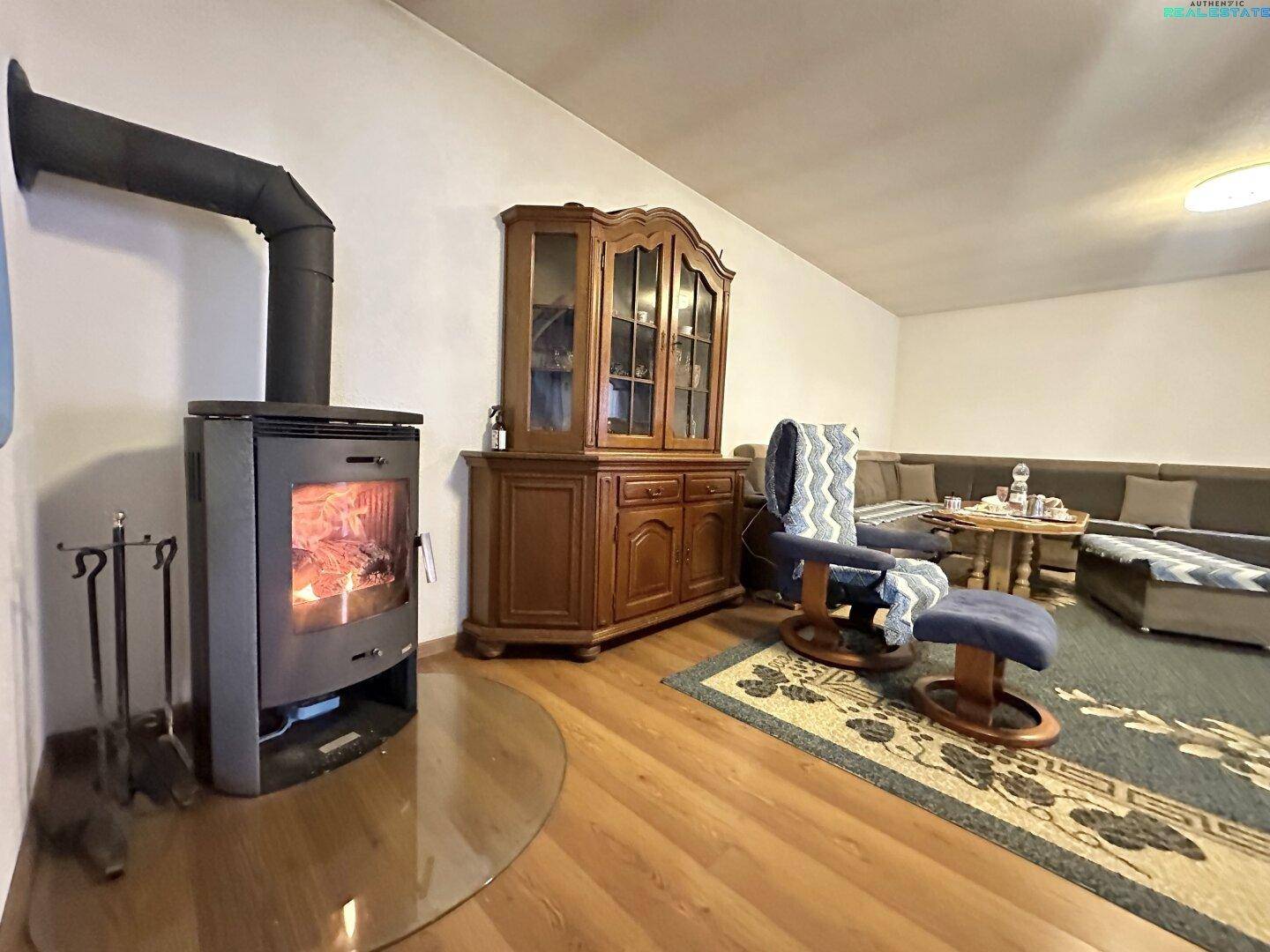 Wohnzimmer mit Kaminofen, traditionellem Holzschrank und bequemer Sitzecke.