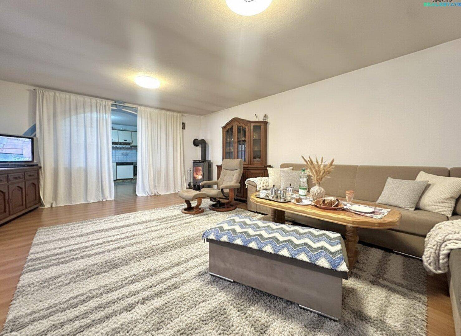 Gemütliches Wohnzimmer mit Kaminofen, großem Teppich und bequemer Sofalandschaft.
