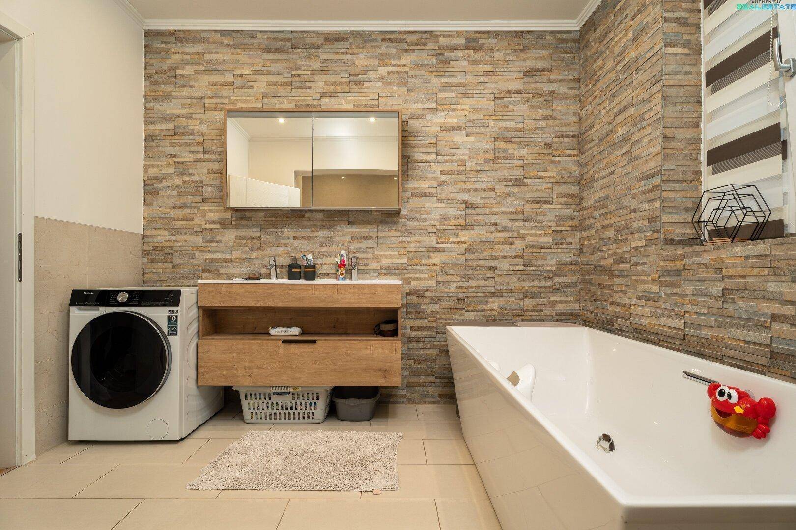 Modernes Badezimmer mit Badewanne, Waschbecken und integrierter Waschmaschine.