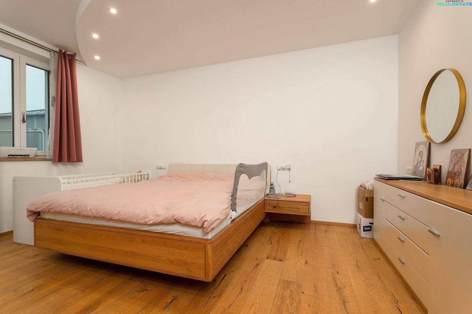 Geräumiges Schlafzimmer mit Holzmöbeln, Parkettboden und viel natürlichem Licht.