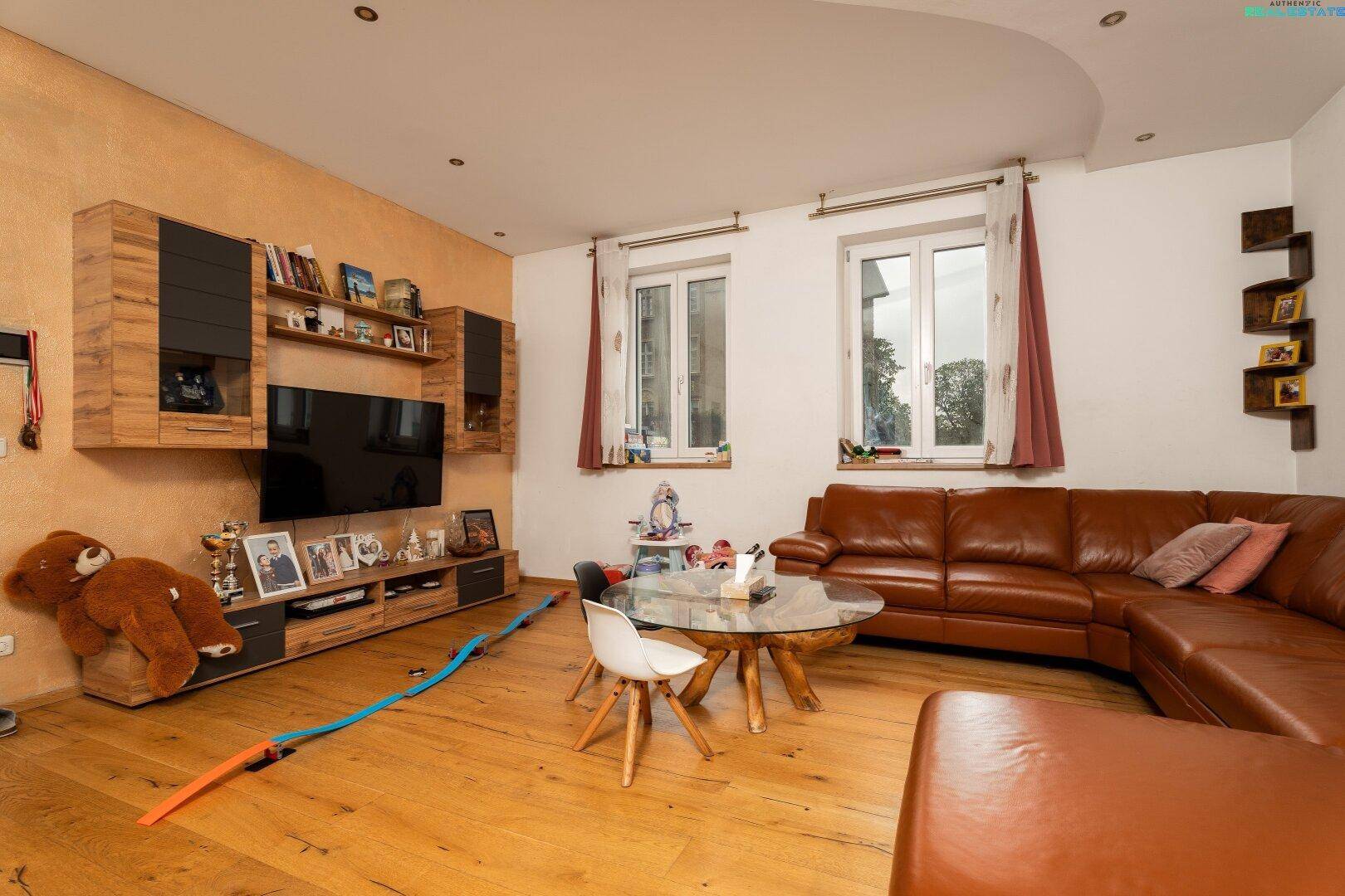 Wohnzimmer mit Unterhaltungselektronik, bequemer Sitzecke und Holzfußboden.