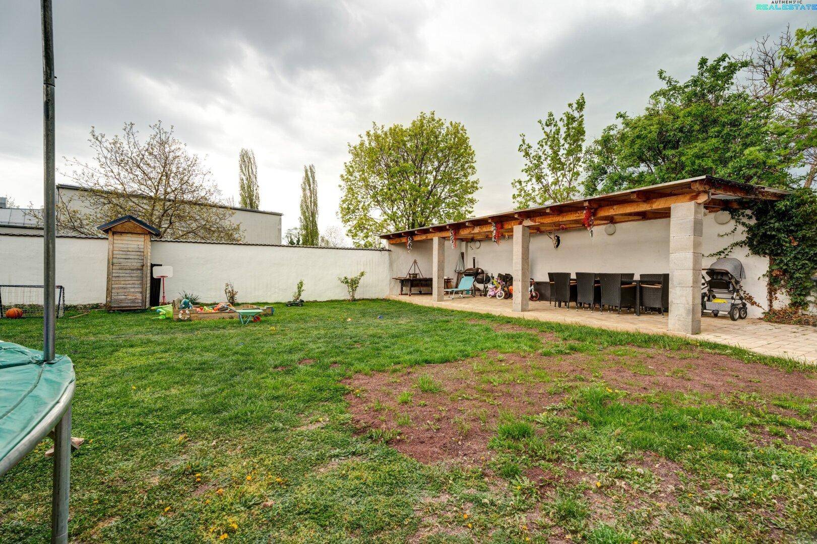 Geräumiger Garten mit überdachter Terrasse, Sandkasten und viel Platz zum Spielen.