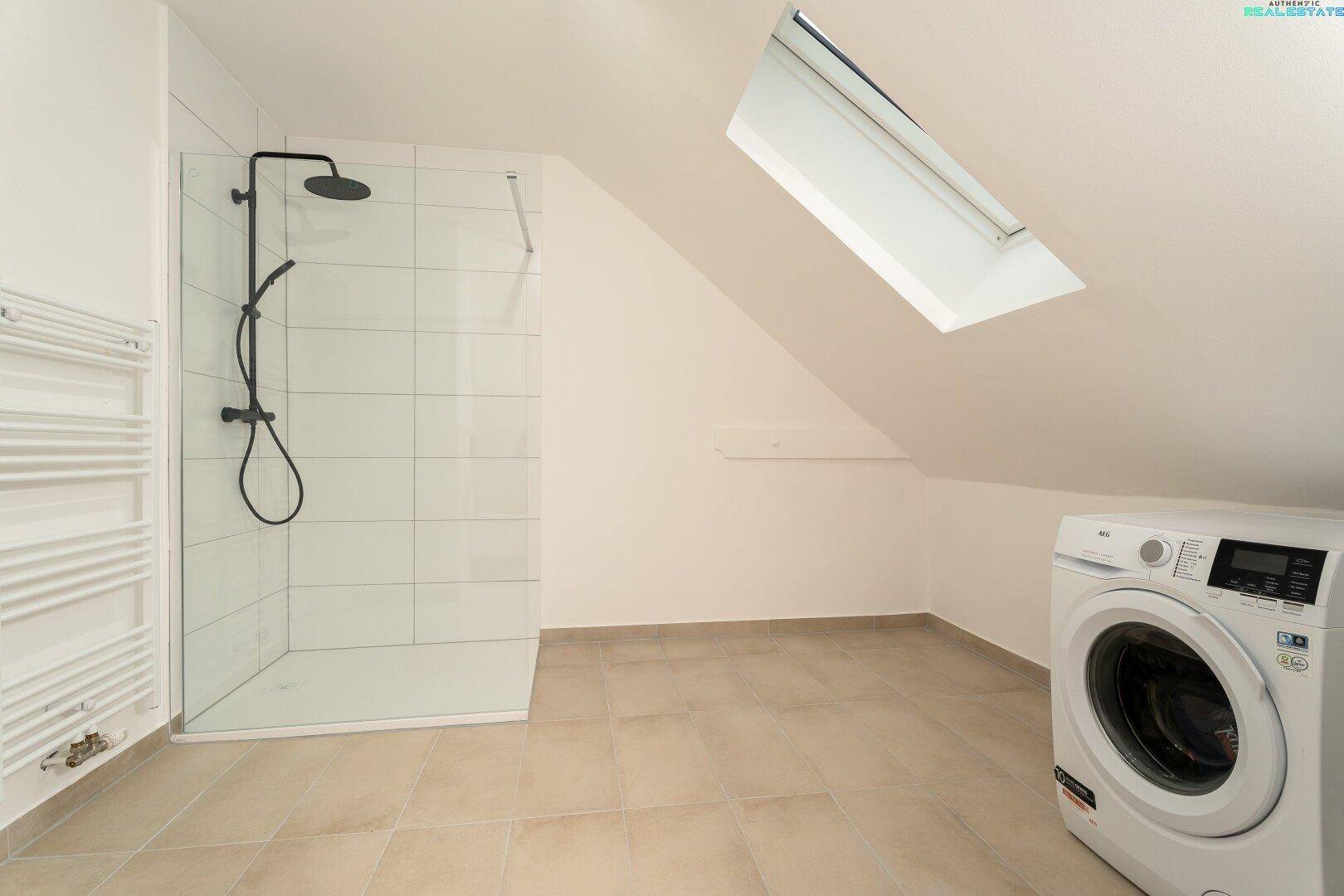 Modernes Dachgeschossbad mit begehbarer Dusche, Waschmaschine und Dachfenster.