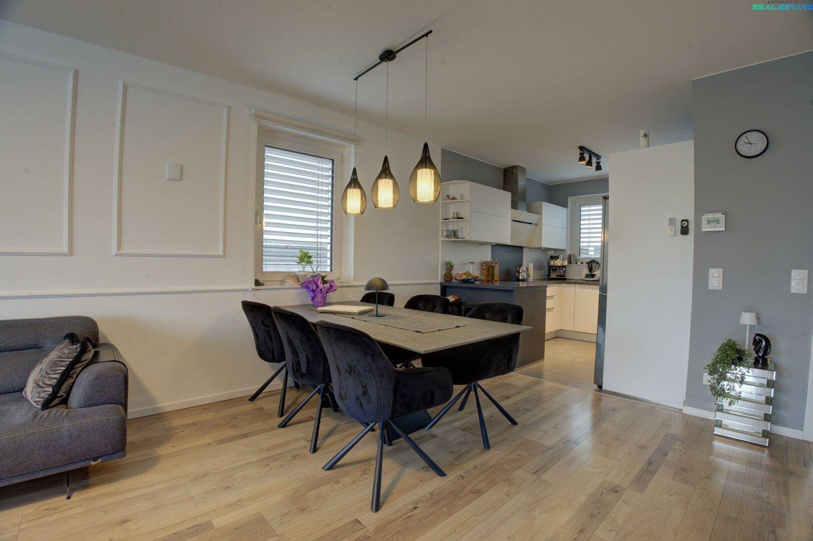 Essbereich mit modernem Tisch und Stühlen, offen zur Küche und mit Holzboden.