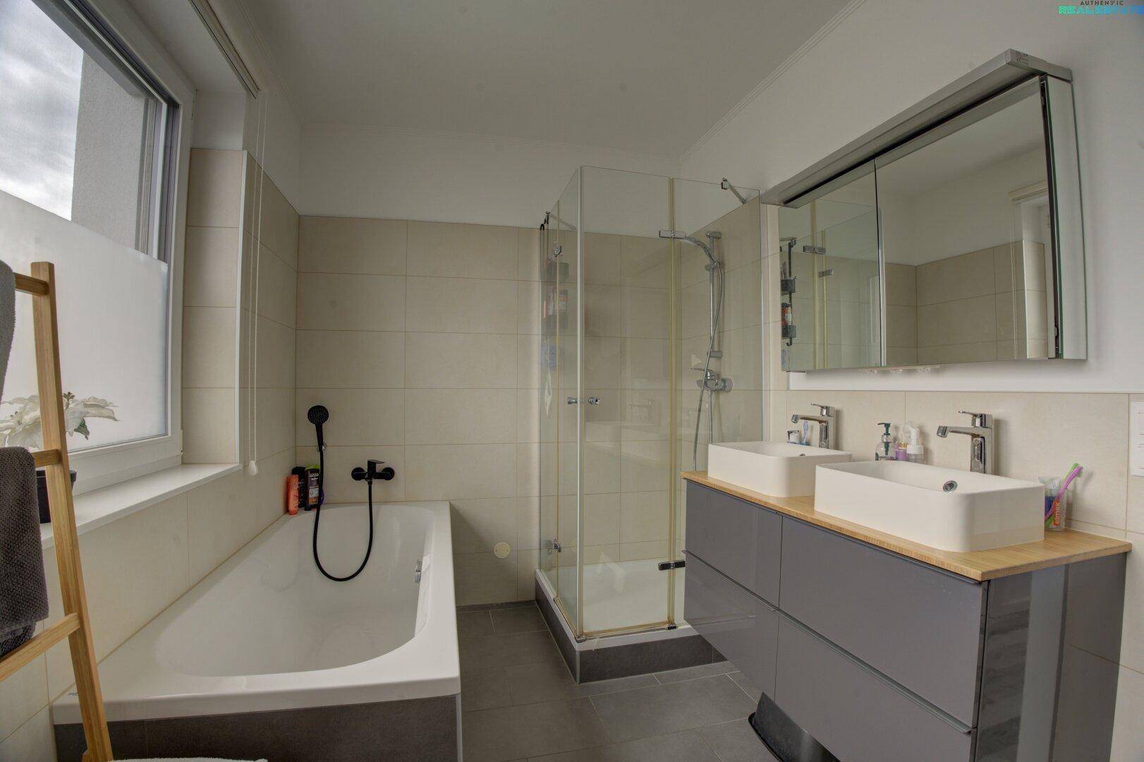 Modernes Badezimmer mit Badewanne, separater Dusche und Doppelwaschbecken.