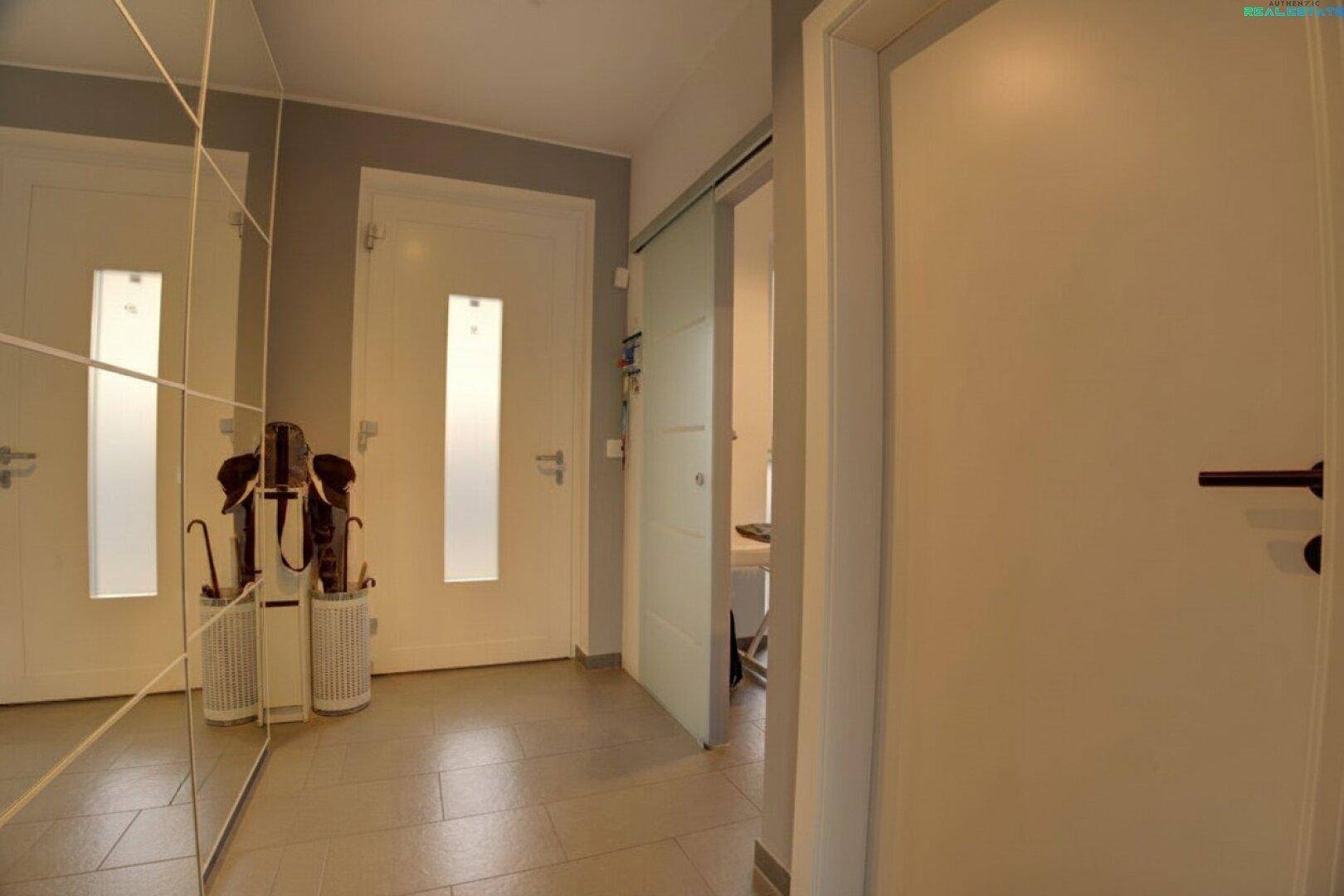Heller Flur mit großem Spiegelschrank, modernen Türen und Fliesenboden, der einladend wirkt.
