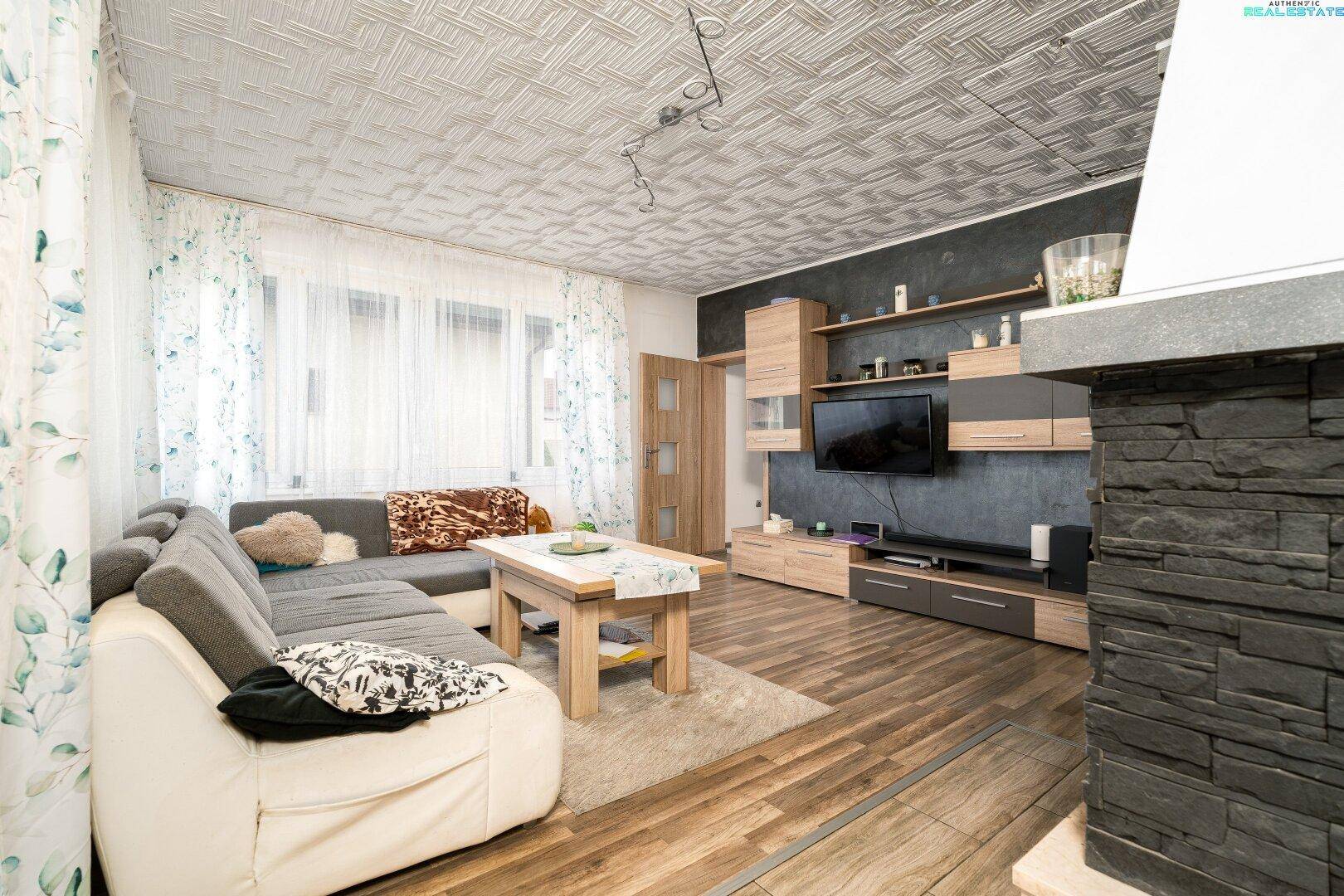 Wohnzimmer mit Ecksofa, Holzboden, TV-Wand und dekorativem Kamin.