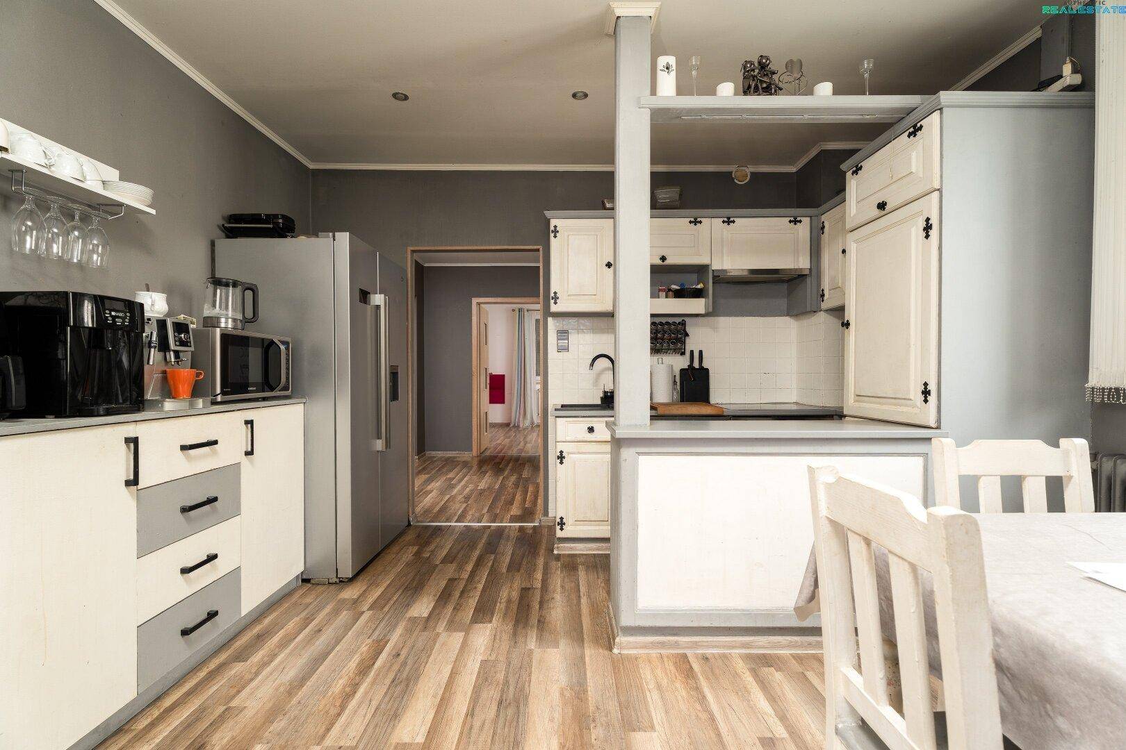 Funktionale Küche mit Holzboden, Essbereich und Blick in den Flur.