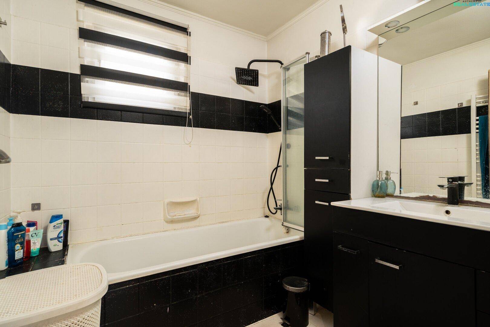 Badezimmer mit Badewanne, Duschvorrichtung und Fenster.