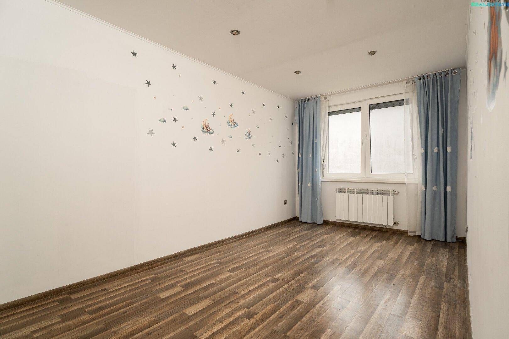 Kinderzimmer mit Holzboden, Fenster und verspielten Wandstickern.
