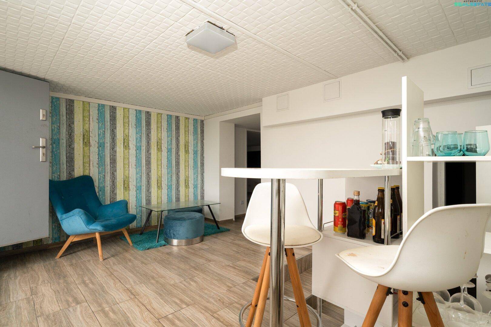 Heller Wohnbereich mit Bar, Holzboden und farbiger Akzentwand.