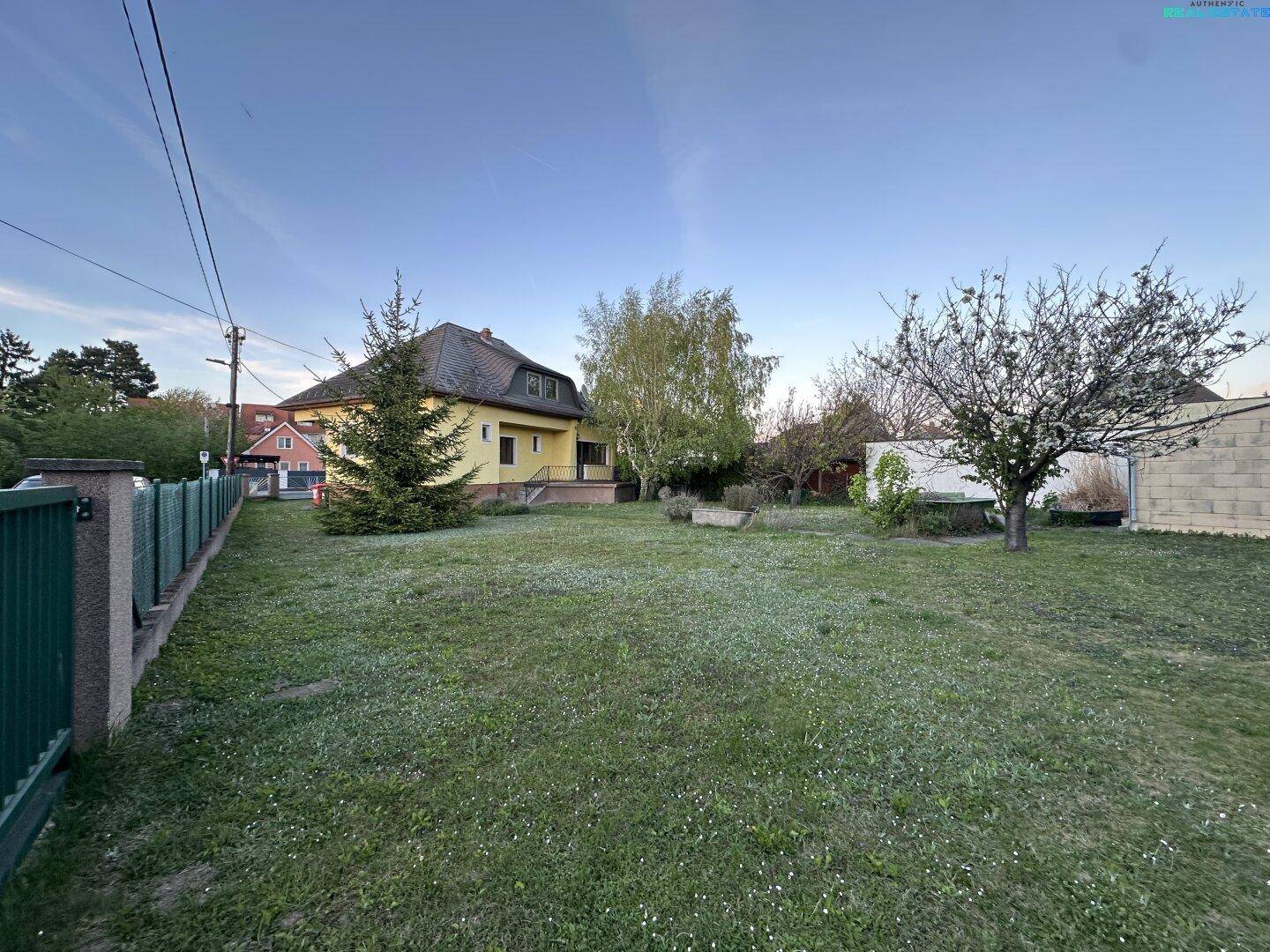 Übersicht über den großen Gartenbereich mit Rasen, Bäumen und dem Haus im Hintergrund.