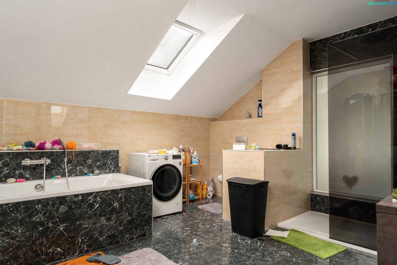 Geräumiges Badezimmer mit Badewanne, Dusche, Waschmaschine und Dachfenster, sehr gut ausgestattet.
