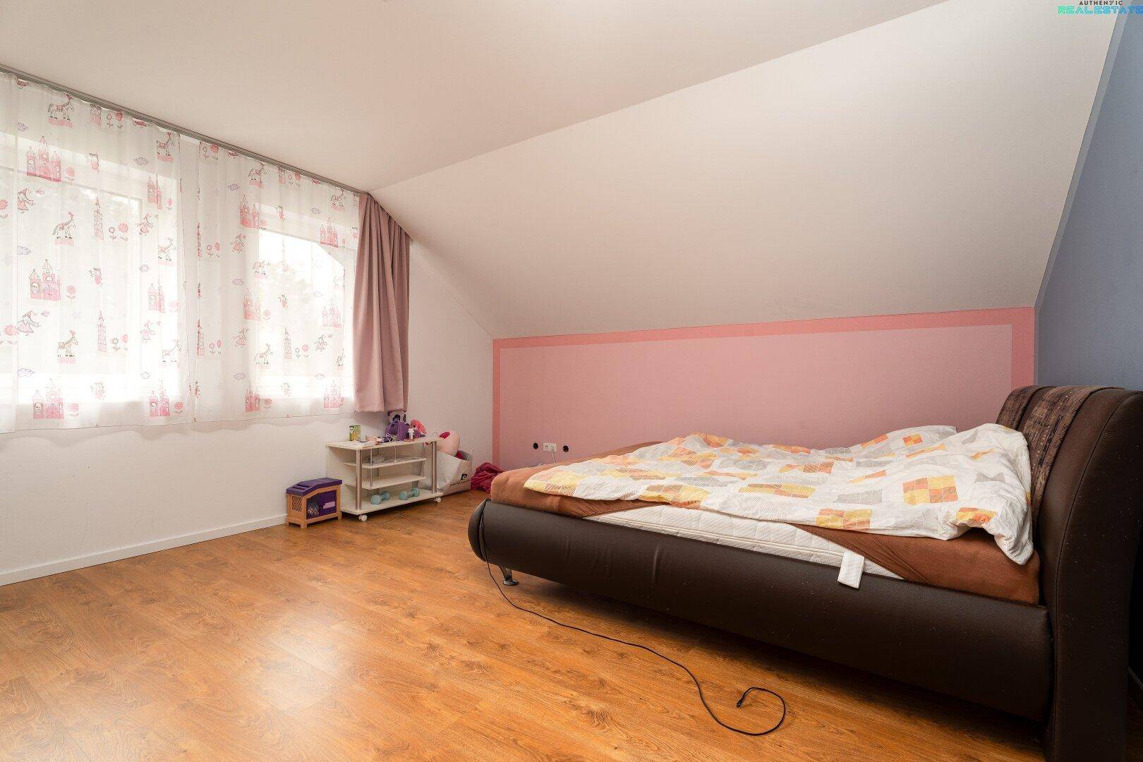 Helles Kinderzimmer im Dachgeschoss mit Holzboden und Fenstern, bietet eine angenehme Lernumgebung.