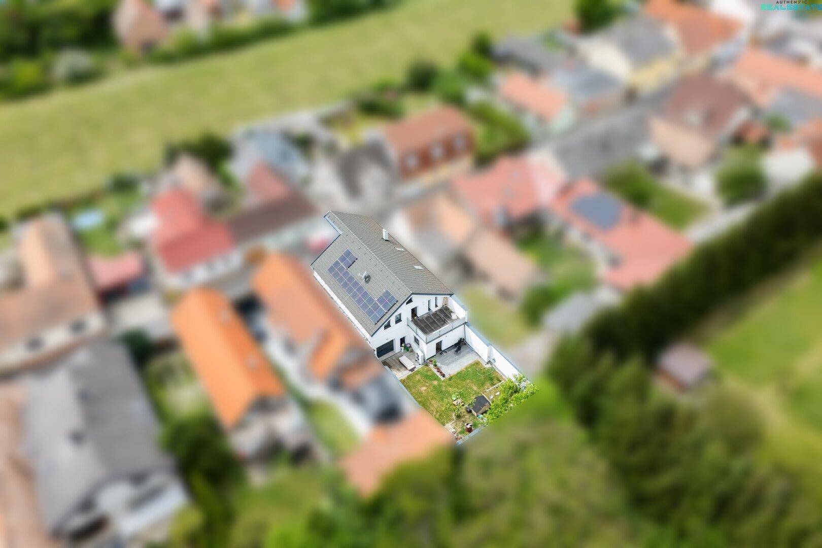 Luftaufnahme des Hauses mit Garten und umliegender Wohnbebauung, eingebettet in die Natur.