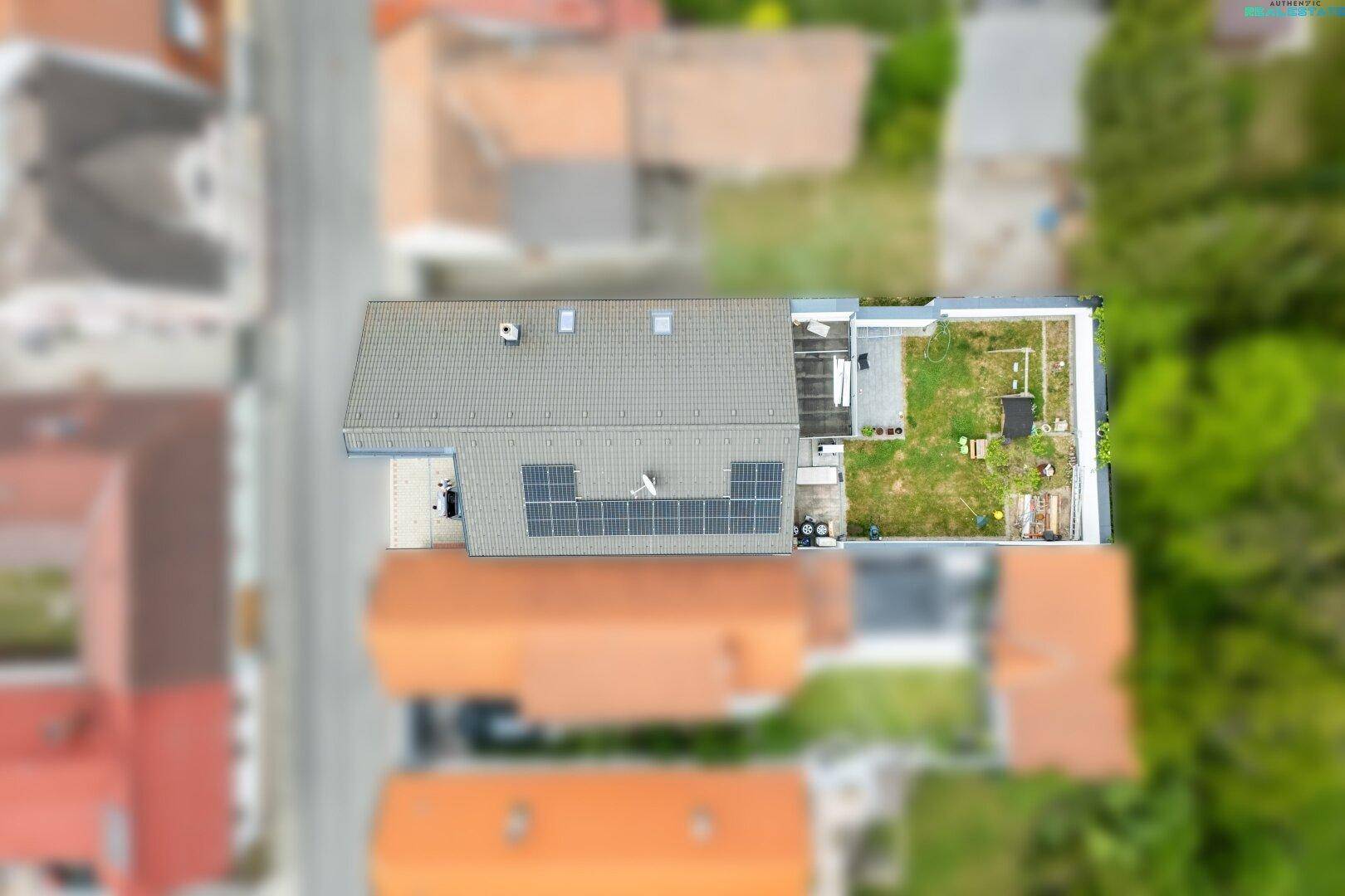 Luftaufnahme des Hauses mit Garten, Terrasse und Solaranlage auf dem Dach, sehr energieeffizient.