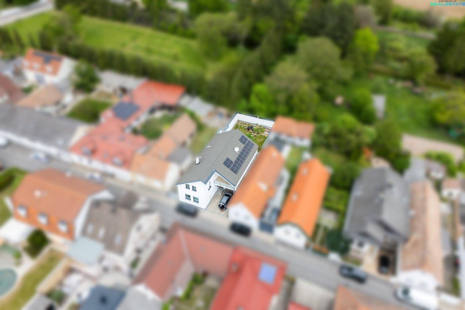 Vogelperspektive des Einfamilienhauses in einer Wohnsiedlung mit viel Grün, idyllische Lage.