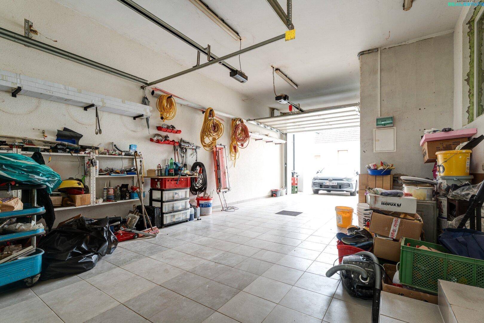 Geräumige Garage mit Fliesenboden und viel Stauraum, bietet Platz für Fahrzeuge und mehr.