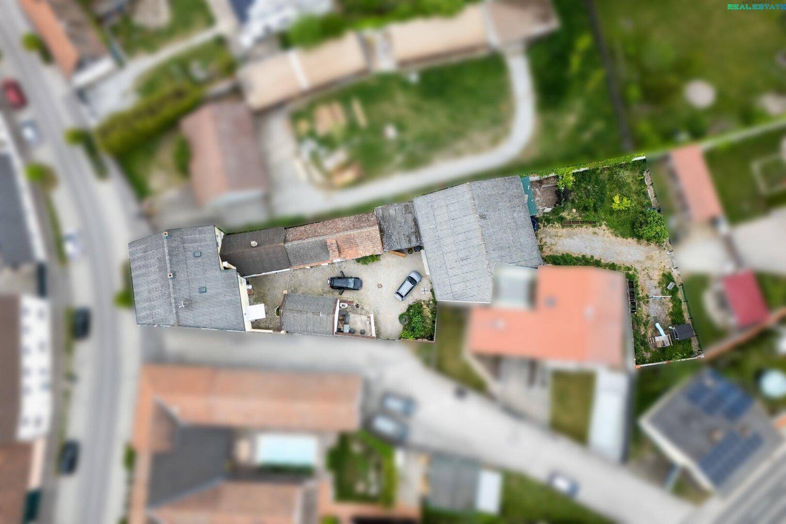 Draufsicht des Anwesens mit Gebäuden, Innenhof und angrenzenden Grünflächen in ländlicher Umgebung.