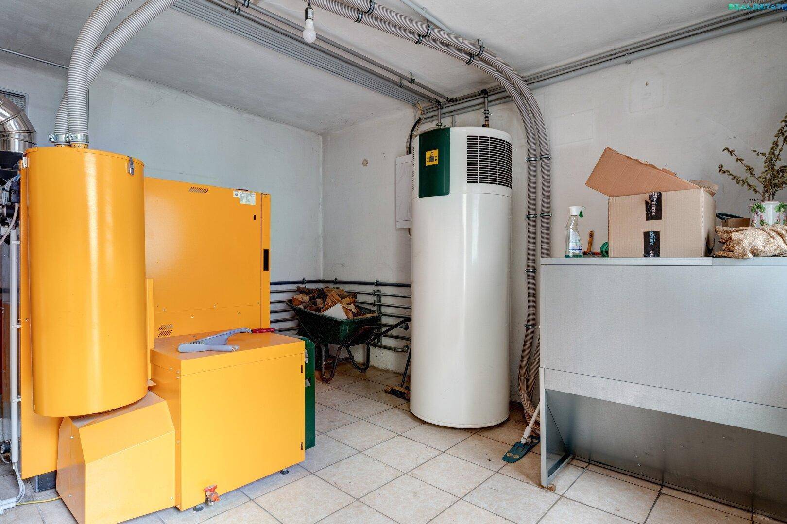 Heizraum mit Pelletheizung, Warmwasserspeicher und gefliestem Boden für die Haustechnik.