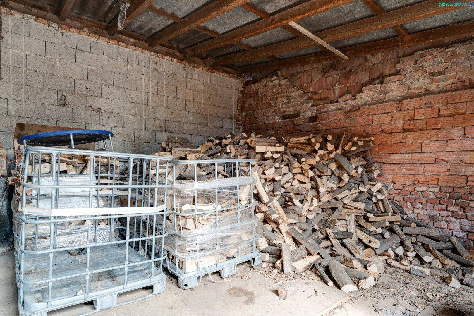 Lagerbereich für Brennholz mit Ziegelwänden und Metallkäfigen zur Aufbewahrung.